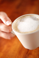 girl keeping a cup of coffee with milk