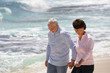 © auremar - Couple de seniors souriants marchant au bord de la plage