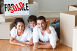 © WavebreakMediaMicro - Happy family lying on the floor after buying house with boxes