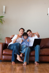 Wall Mural - Parents and kid having fun with a laptop and copy-space