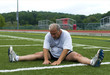 middle age man stretching and exercising on sports field