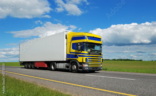Naklejka samoprzylepna Pojedyncza ciężarówka z niebiesko-żółtą kabiną poruszającą się po autostradzie.