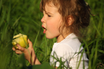 Wall Mural - girl eats green apple in grass