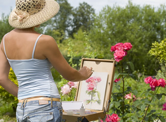 Young woman painting roses in the garden