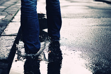 Person Is Walking In The Streets And Through A Puddle