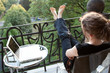junge blonde Frau entspannt, Füße hoch, vor Laptop auf Balkon