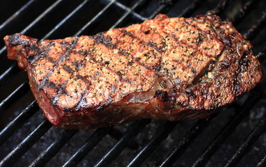 Good looking steak cooking on open grill