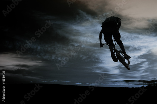 Fototapeta na wymiar Ekstremalny skoczek na rowerze na tle chmur