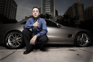 Handsome man posing at night by a car on the street