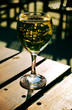 Sunlit white wine glass on a wooden table outdoors