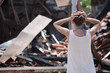 woman stands in front of burned out house