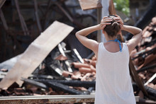 Woman Stands In Front Of Burned Out House