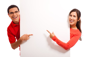 Wall Mural - Happy young couple pointing to copy space