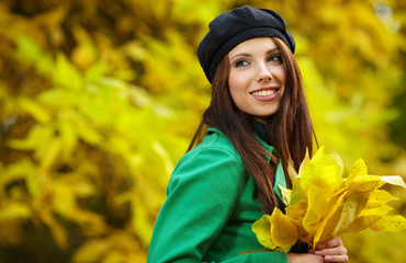 Sticker - Fashion woman in autumn park holding yellow leaf