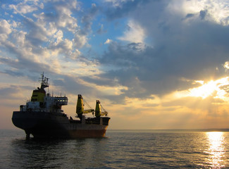 Beautiful sunset with dry cargo ship setting out on its journey