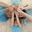 © WavebreakMediaMicro - High angle of family on floor with heads and hands together