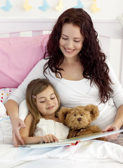 Wall Mural - Happy mother and daughter reading in bed