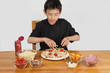 © Ann Stephenson - young asian boy making home-made pizza