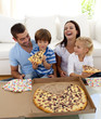 © WavebreakMediaMicro - Parents and children eating pizza in living-room