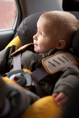 Adorable little boy sitting in the safety carseat