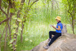 © Jed Share/Kaoru Share/Blend Images - Asian woman sitting on rock
