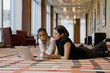 © Mark Edward Atkinson/Blend Images - Multi-ethnic businesswomen laying on floor working on laptop