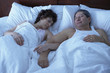© Trevor Lush/Blend Images - Multi-ethnic couple sleeping in bed arm in arm