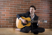Businessman Sits With A Guitar On The Floor And Sings