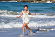 Beautiful young girl runs in the water on Bondi Beach