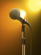 Microphone on stand with orange stage lights.