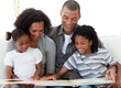 © WavebreakMediaMicro - Afro-American family reading a book in the living-room