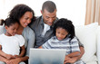 © WavebreakMediaMicro - Afro-American family using a laptop on the sofa