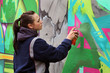 Graffiti Artist: Jugendliche sprüht mit Sprühdose Graffiti an die Wand