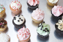 A Dozen Assorted Cupcakes On Silver Surface