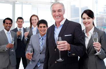 Smiling inernational business team holding glasses of Chamoagne