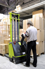 Operator of electric forklift stacker in warehouse