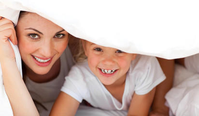 Wall Mural - Happy mother and her blond girl playing together on a bed