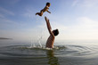 father is tossing up a child in water