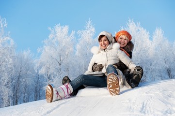 Mother and daughter sliding in the snow