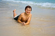 © travelview - young boy is lying at the beach and enjoying the  water