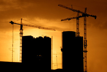 building construction with cranes and back lit by setting sun