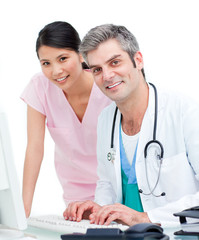 Smiling doctor and nurse working at computer