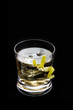 Rusty nail cocktail with lemon peel on a black background