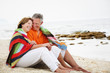 © hannamonika - Happy mature couple sitting on the beach.