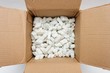 © slavapolo - A cardboard box with packing foam pellets top view..