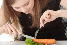 Young Woman Eating Carrot From Plate