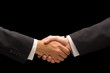 © Jose Luis Stephens - Executives handshake against a black background