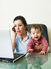 businesswoman on the phone, holding daughter