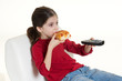 bambina con telecomando che mangia una pizza