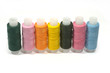Seven colored spools of sewing thread on a white background